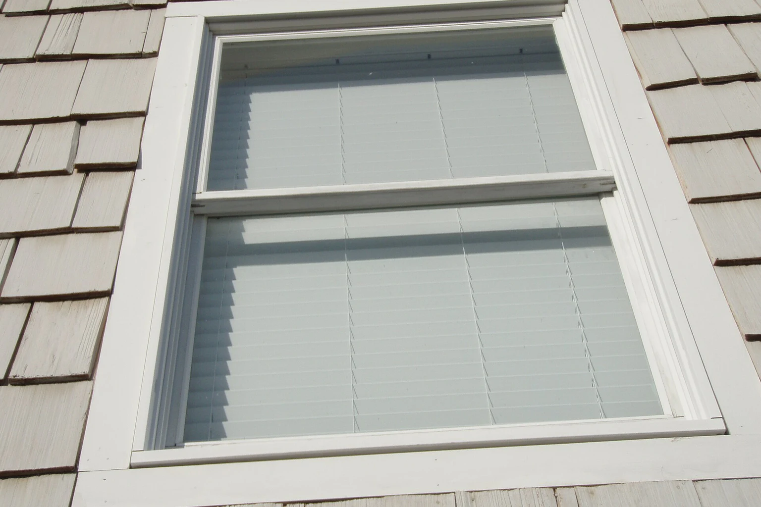 Exterior close-up of a finished white double-hung window and surrounding trim