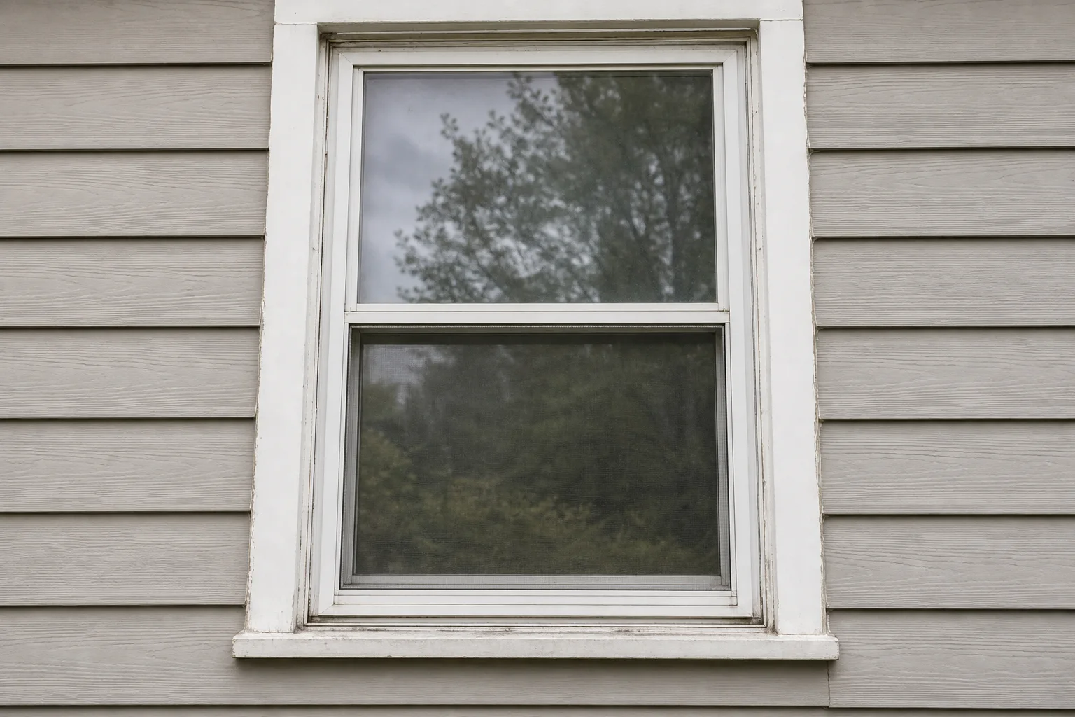 Before: older double-hung window with weathered exterior trim and a lower window screen.